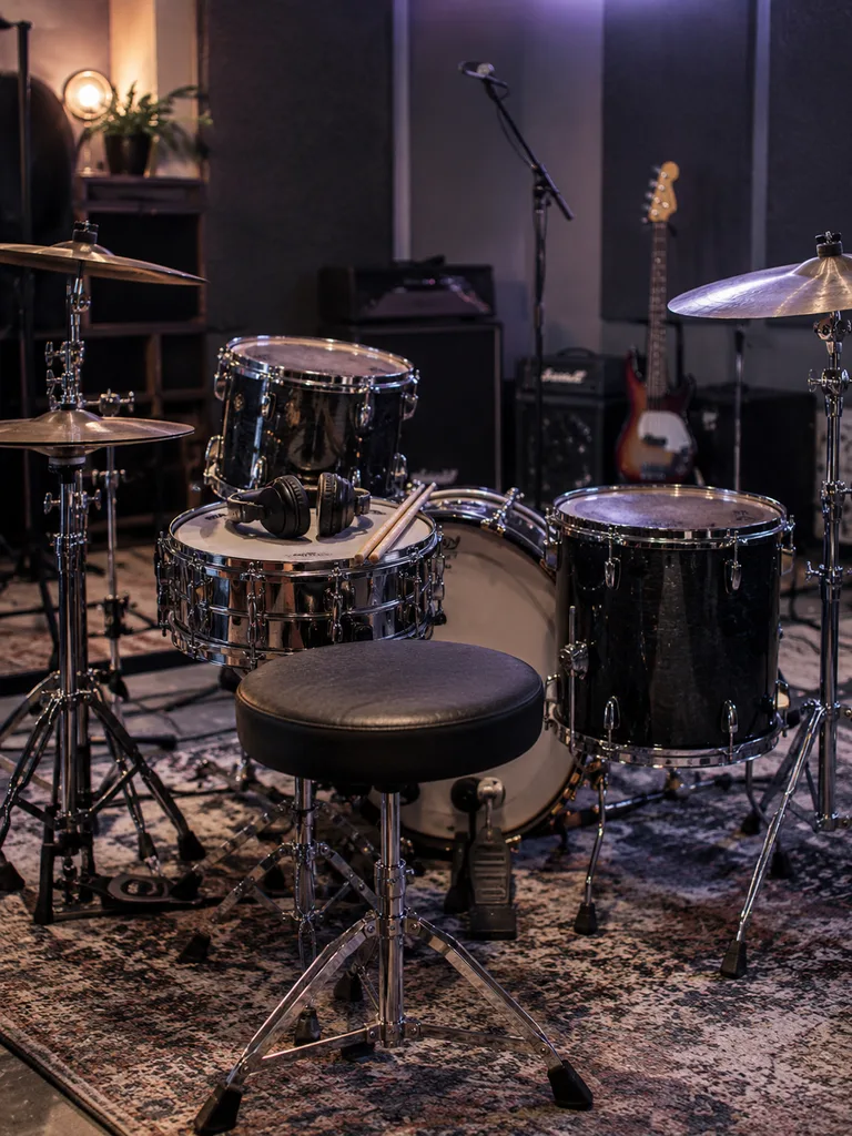 Lege drumkruk in een repetitieruimte met microfoons en basinstrumenten